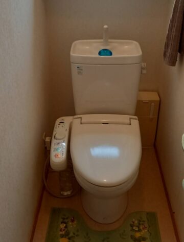 alt="【三重県四日市市】トイレ交換工事 施工前 ウォシュレットのホースから水漏れが発生している既設トイレの状態"